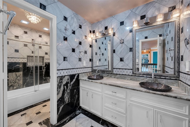 bathroom featuring vanity, combined bath / shower with glass door, and tile walls