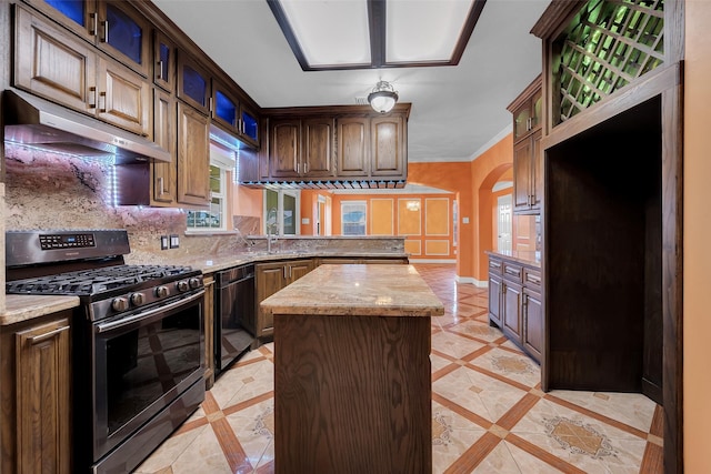 kitchen featuring stainless steel gas range, a center island, black dishwasher, light stone counters, and decorative backsplash