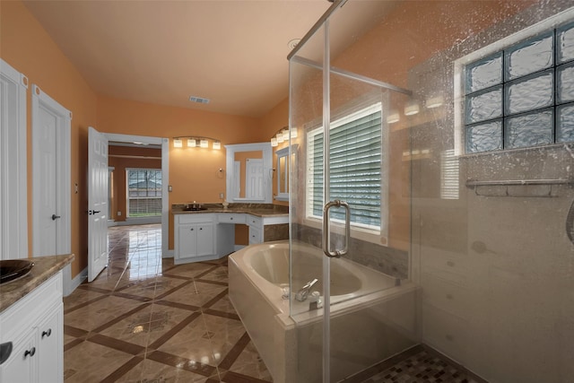 bathroom featuring independent shower and bath, vanity, and a healthy amount of sunlight