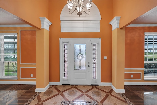 entryway with ornamental molding, a towering ceiling, and an inviting chandelier