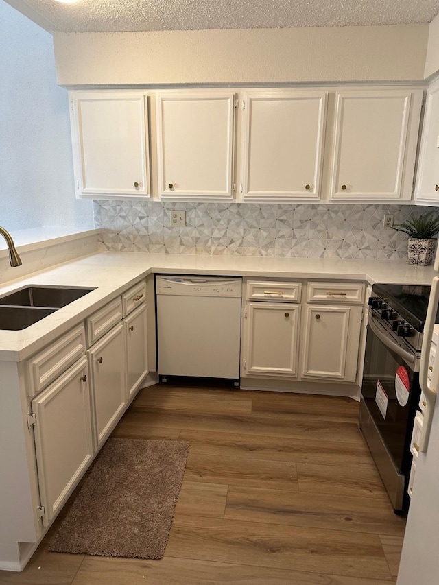 kitchen featuring range with electric cooktop, white cabinets, wood finished floors, white dishwasher, and a sink