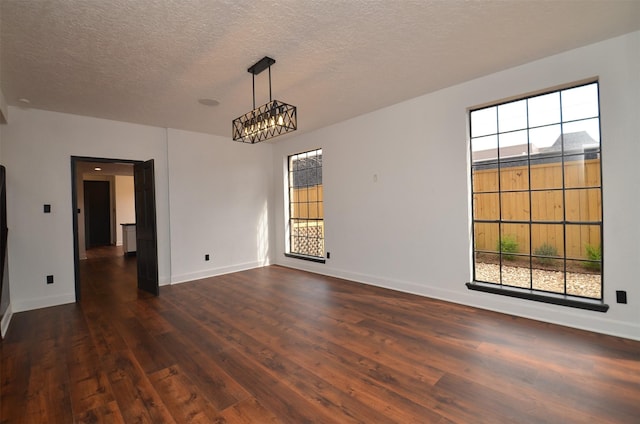 unfurnished room with a textured ceiling, baseboards, and dark wood-style flooring