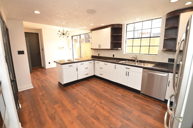 kitchen with white cabinetry, sink, dark hardwood / wood-style flooring, kitchen peninsula, and stainless steel appliances