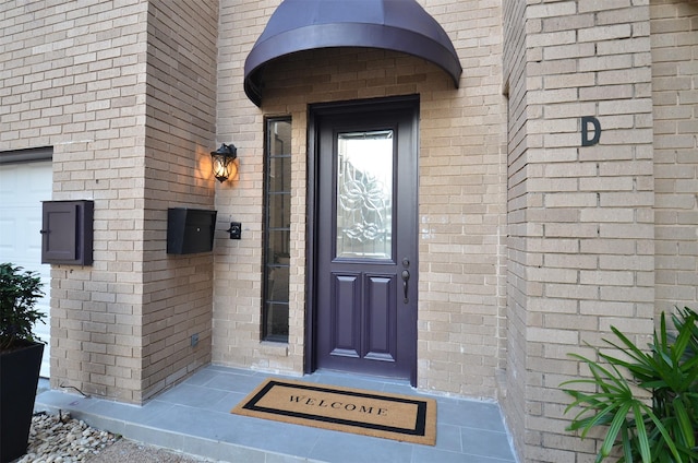 view of exterior entry featuring brick siding