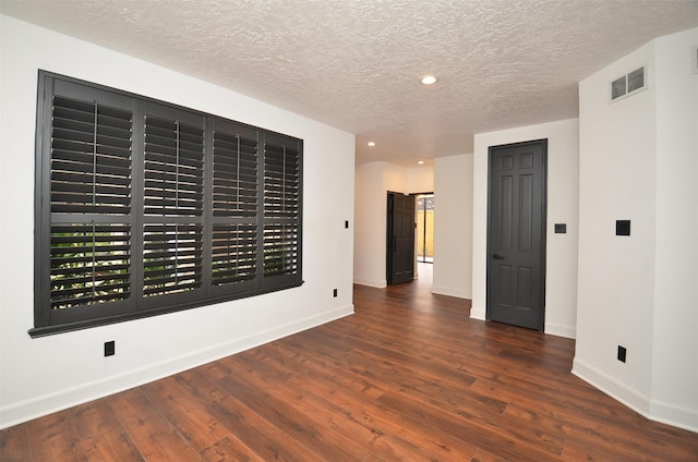 unfurnished room featuring dark wood-type flooring and a textured ceiling