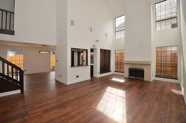 unfurnished living room with dark wood-type flooring, stairway, a fireplace, and baseboards