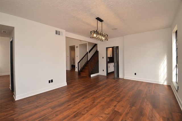 empty room with dark wood-style floors, visible vents, stairs, and baseboards