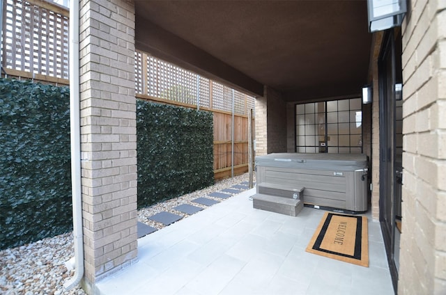 view of patio featuring fence and a hot tub