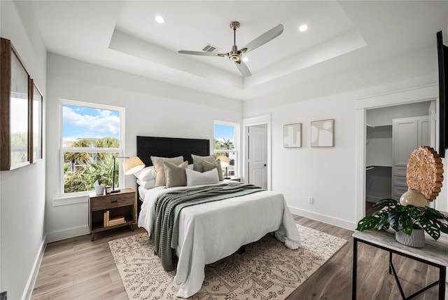 bedroom with a tray ceiling, light hardwood / wood-style floors, and ceiling fan