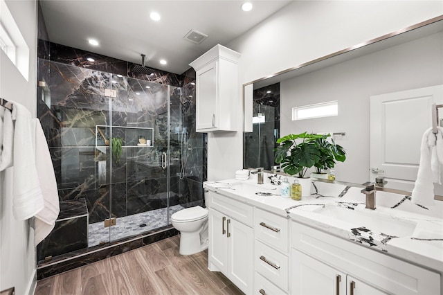 bathroom with vanity, hardwood / wood-style floors, a shower with shower door, and toilet