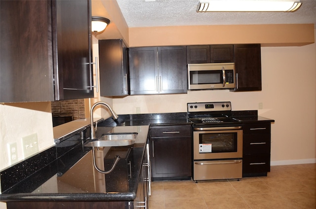 kitchen with sink, appliances with stainless steel finishes, dark brown cabinetry, a textured ceiling, and light tile patterned flooring