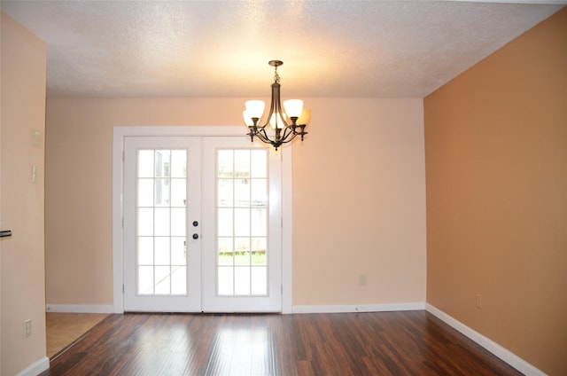 entryway featuring dark hardwood / wood-style floors, a textured ceiling, a chandelier, and french doors