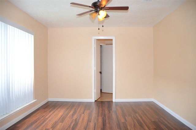 empty room with a wealth of natural light, dark wood-type flooring, and a textured ceiling