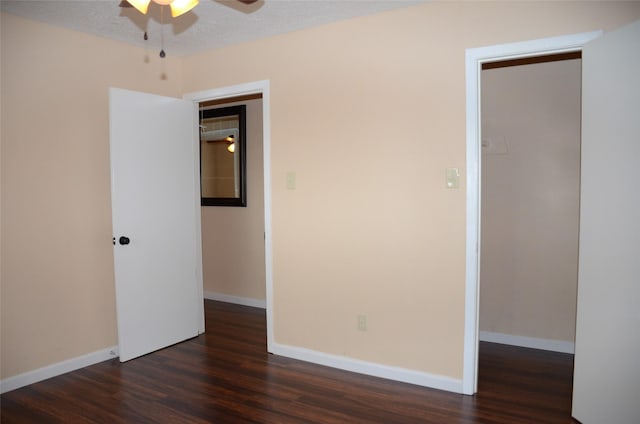 empty room featuring ceiling fan, dark wood-type flooring, and a textured ceiling