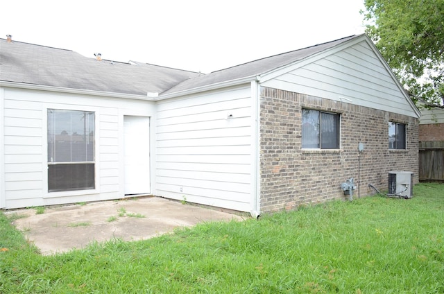 view of side of property featuring central AC, a patio area, and a lawn