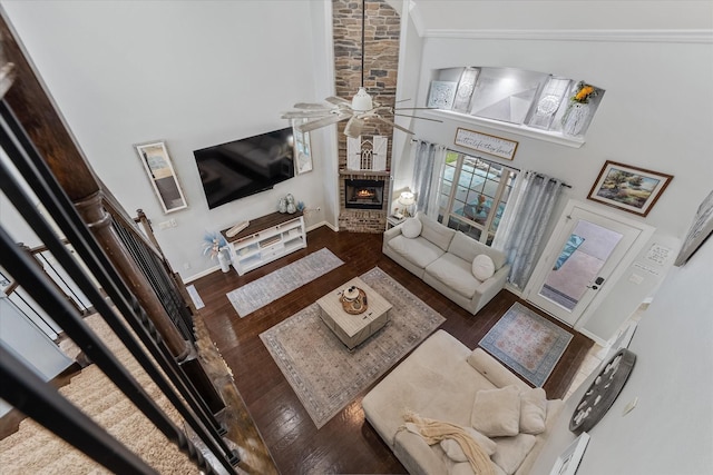 living room with a high ceiling, a large fireplace, dark wood-type flooring, and ceiling fan