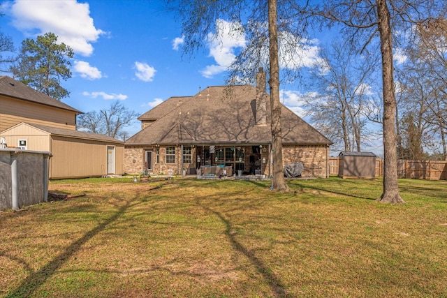 back of house featuring a storage shed and a yard