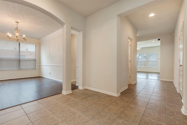 interior space with a chandelier, arched walkways, baseboards, and light tile patterned floors