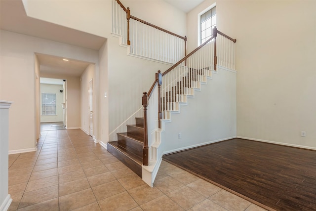 stairway with tile patterned floors and a high ceiling