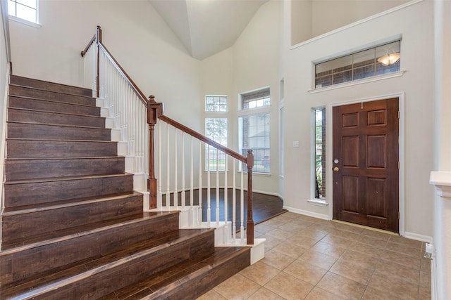 tiled foyer entrance featuring high vaulted ceiling