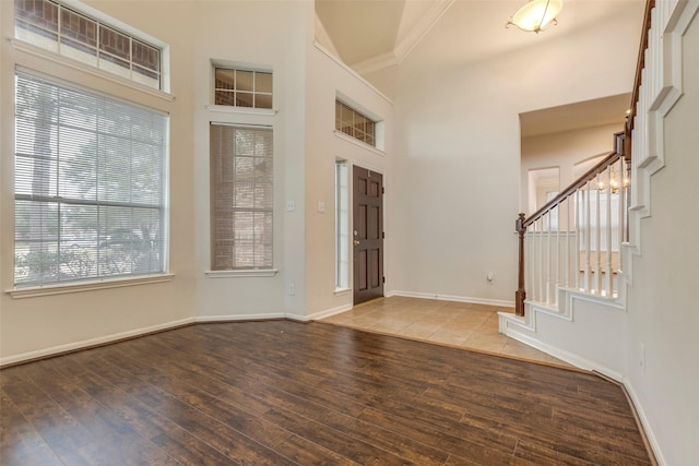 entrance foyer featuring hardwood / wood-style flooring, a towering ceiling, and crown molding