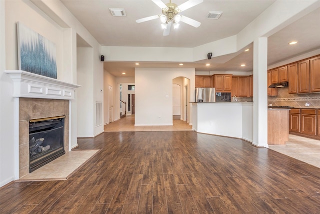 unfurnished living room featuring a fireplace, ceiling fan, and light hardwood / wood-style flooring