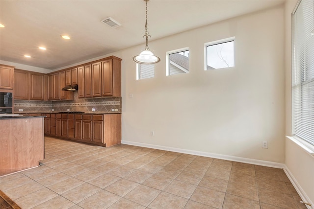 kitchen with black microwave, pendant lighting, light tile patterned floors, and decorative backsplash