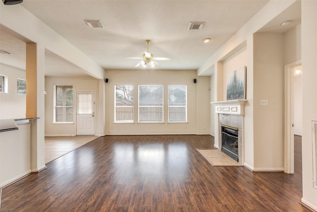 unfurnished living room featuring a tile fireplace, ceiling fan, and dark hardwood / wood-style flooring