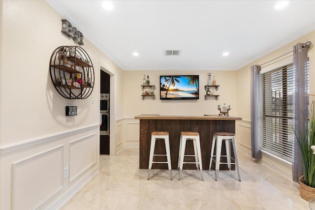 bar featuring ornamental molding and double oven