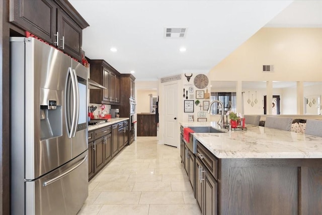 kitchen featuring sink, dark brown cabinets, a spacious island, and appliances with stainless steel finishes