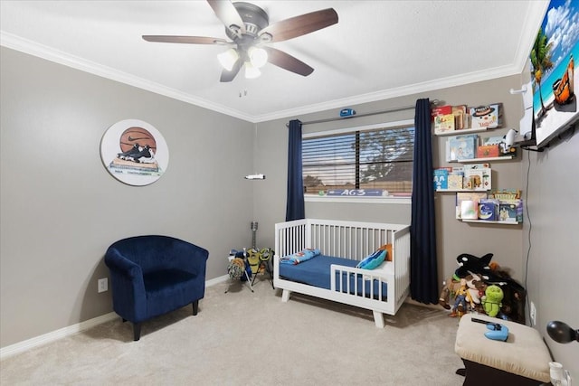 bedroom featuring ornamental molding, a nursery area, light carpet, and ceiling fan