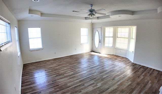 unfurnished room featuring dark wood-type flooring, ceiling fan, and a tray ceiling