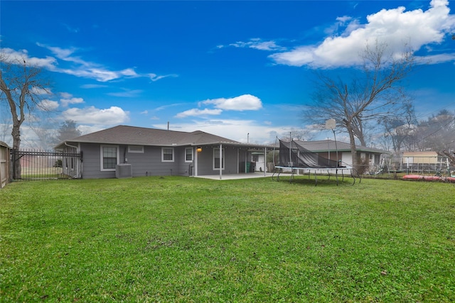 rear view of house with a yard, cooling unit, a trampoline, and a patio area