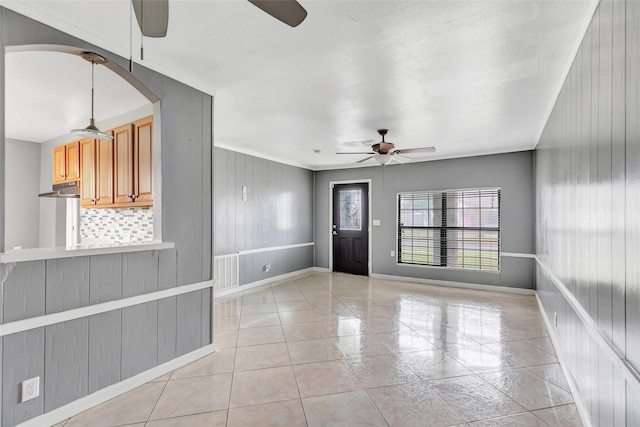 interior space with ceiling fan and wood walls