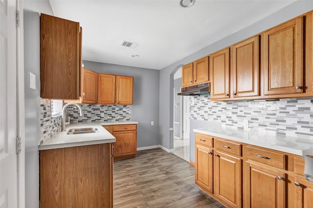 kitchen featuring tasteful backsplash, sink, and light wood-type flooring