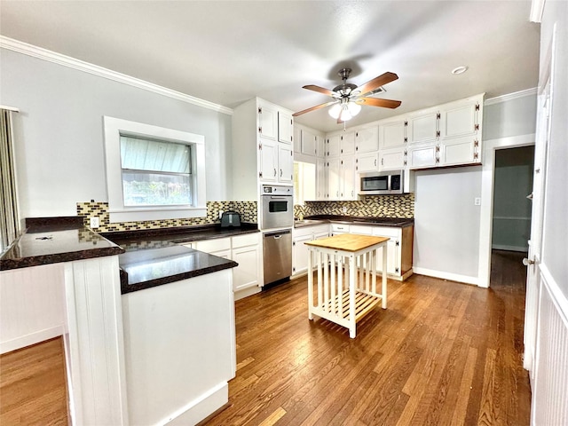 kitchen featuring stainless steel appliances, crown molding, hardwood / wood-style floors, and white cabinets