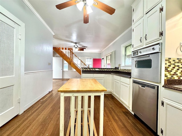 kitchen with white cabinetry, crown molding, dark wood-type flooring, and stainless steel appliances