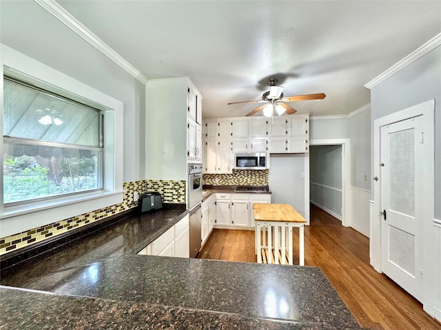 kitchen with crown molding, hardwood / wood-style flooring, white cabinets, and appliances with stainless steel finishes