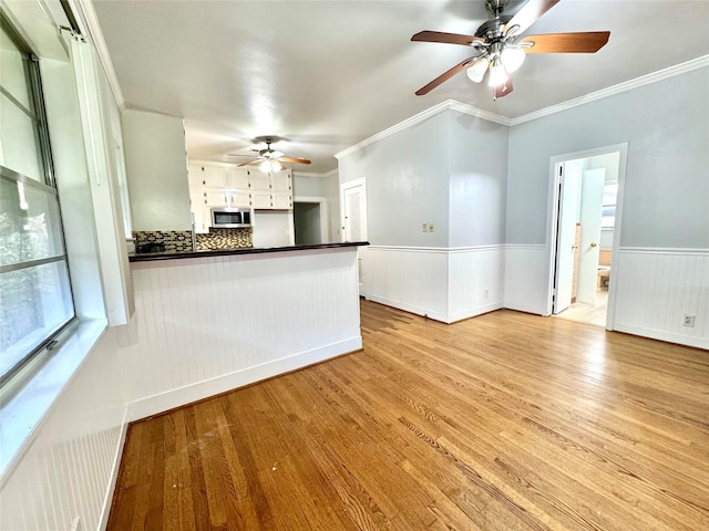 unfurnished living room featuring crown molding, ceiling fan, and light hardwood / wood-style flooring