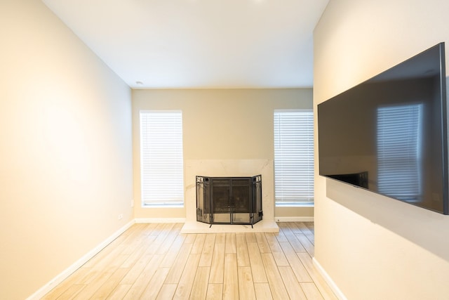 unfurnished living room with a high end fireplace and light wood-type flooring