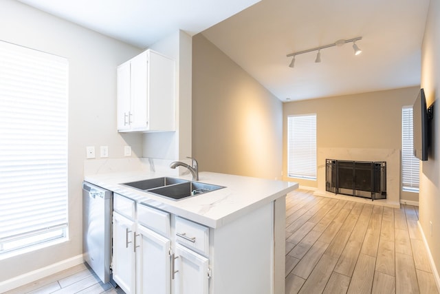 kitchen with sink, white cabinetry, light hardwood / wood-style flooring, track lighting, and dishwasher