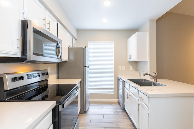 kitchen featuring sink, light hardwood / wood-style flooring, appliances with stainless steel finishes, light stone countertops, and white cabinets