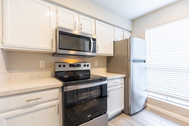 kitchen featuring appliances with stainless steel finishes, light hardwood / wood-style floors, and white cabinets