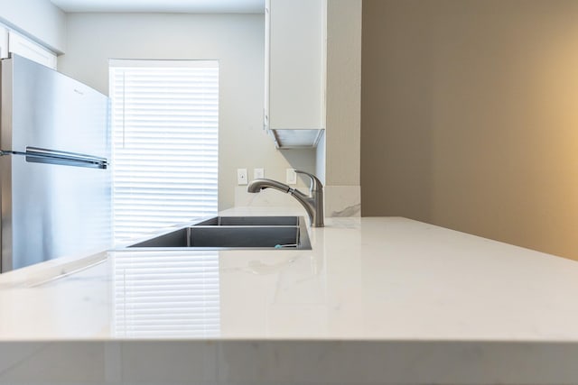 kitchen featuring sink, white cabinets, and stainless steel refrigerator