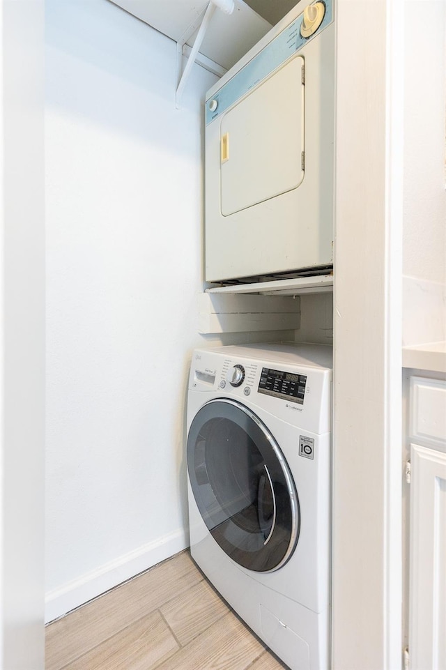 washroom with stacked washer / drying machine and light wood-type flooring