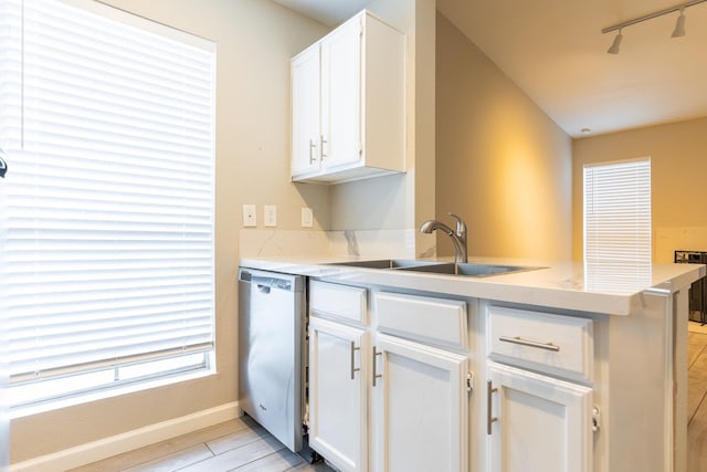 kitchen featuring sink, stainless steel dishwasher, kitchen peninsula, and white cabinets