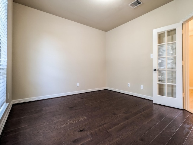 unfurnished room featuring dark wood-style floors, visible vents, and baseboards