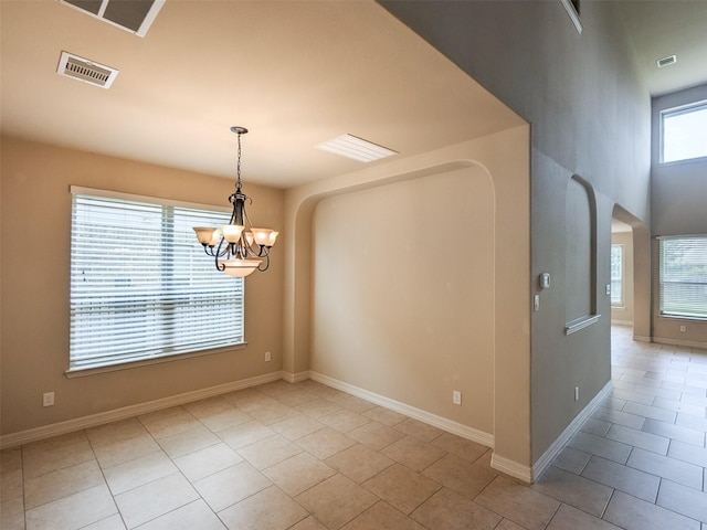 unfurnished room featuring light tile patterned floors, baseboards, visible vents, arched walkways, and a chandelier