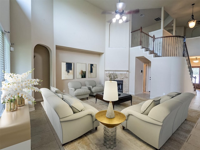 living room with a high ceiling, ceiling fan, tile patterned floors, and a fireplace