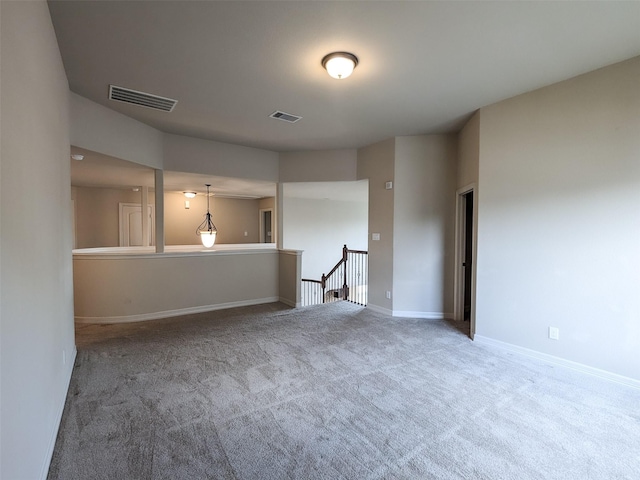 spare room with carpet floors, visible vents, and baseboards